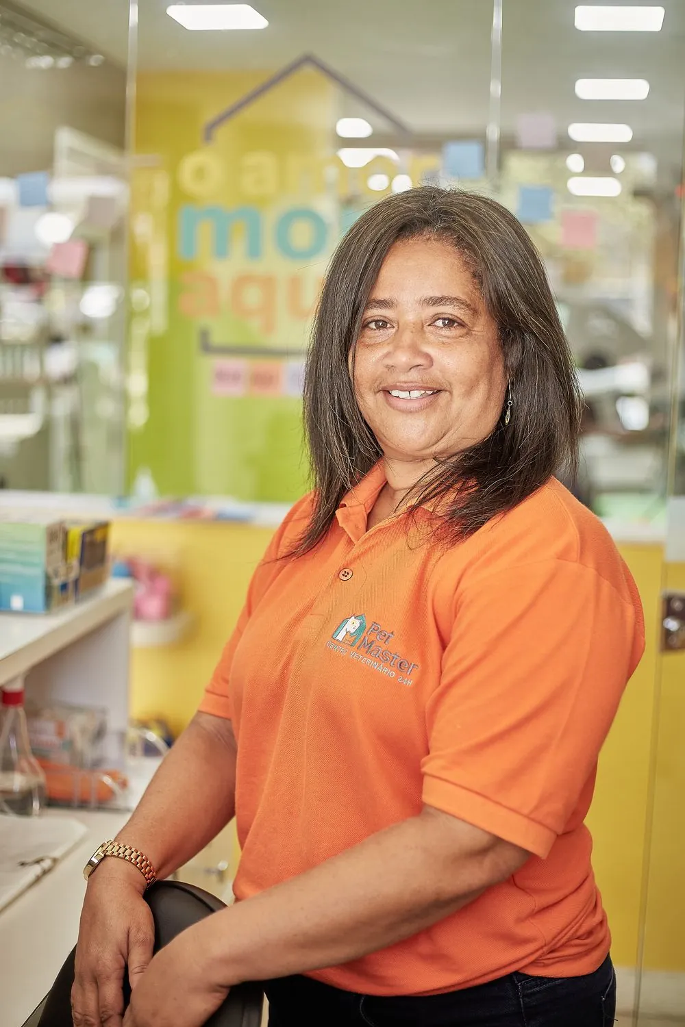 Funcionária da Pet Master em frente ao painel O Amor Mora Aqui